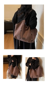 Nahaufnahme der braunen Wildledertasche mit silbernen Nieten und Quasten-Kordelzug