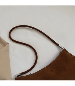 Détail du sac bandoulière en daim marron avec fines bretelles et boucles argentées