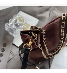 Gros plan sur la chaîne dorée et le daim marron d'un sac seau à cordon au style raffiné