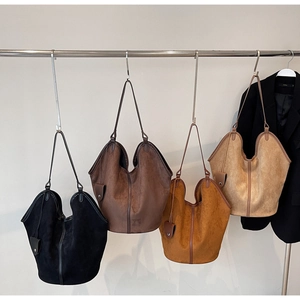 Close-up of four suede tote bags in black, coffee, caramel and beige with minimalist stitching