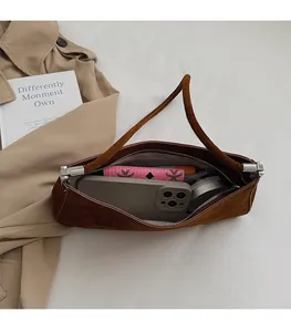 Détail de l'intérieur d'un sac hobo en daim marron avec téléphone et portefeuille