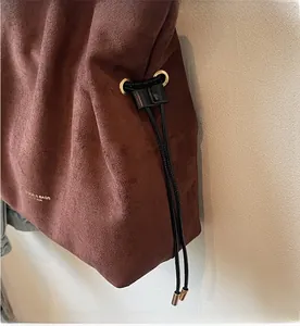 Détail du sac seau en daim marron foncé avec embouts en métal doré et cordon de serrage