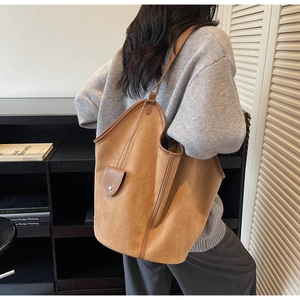 Detail view of large brown suede tote bag with leather trim and metal snap button
