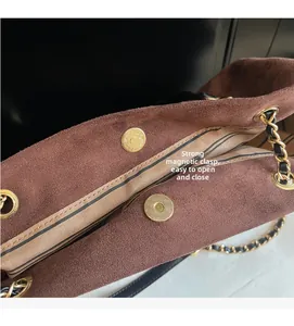 Détail du sac seau en daim marron avec doublure rayée et fermeture magnétique dorée