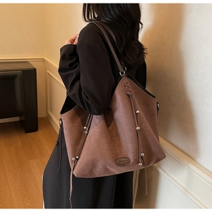 Close-up of brown suede tote bag featuring delicate drawstring tassels and metallic beads