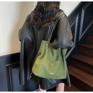 Détail du sac seau en daim vert avec bandoulière chaîne noire et cordon de serrage