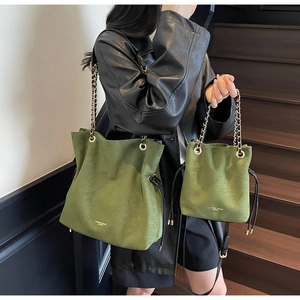 Détail du sac seau en daim vert rétro avec bandoulière chaîne dorée sur mannequin