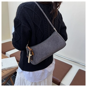 Detail of grey suede hobo bag featuring decorative wooden beads and silver hardware