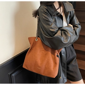 Gros plan sur le sac seau en daim marron avec chaîne en métal porté par un mannequin