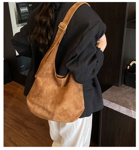 Détail d'un sac cabas en daim marron avec bandoulière et boucle de réglage dorée