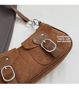 Primer plano de bolso de gamuza marrón con hebillas metálicas y textura suave