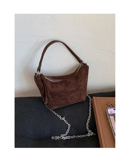 Close-up of vintage brown suede dumpling bag with silver chain strap and matte texture