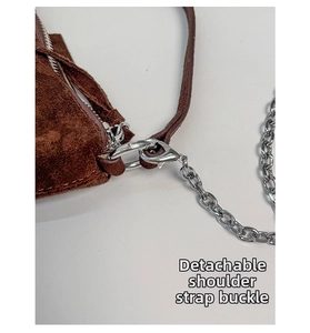 Macro detail of the silver detachable shoulder strap buckle on a brown suede bag