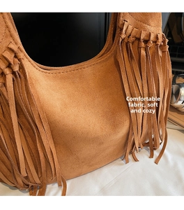 Gros plan sur un sac bandoulière en daim marron avec franges bohèmes et texture douce