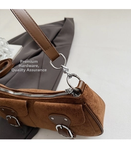Détail du sac croissant vintage en daim marron avec boucles et fermetures en métal argenté