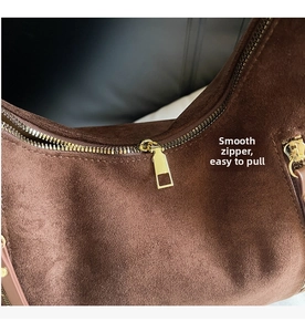 Macro shot of smooth gold zipper hardware and brown suede texture on the backpack detail