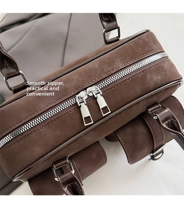 Close-up of dual metal zippers and matte brown leather texture on a retro Boston bag