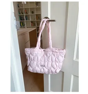 Close-up of heart-shaped quilting and metal logo on a light pink tote bag