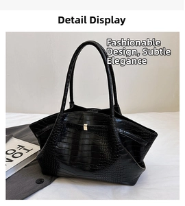 Detail of black crocodile texture bag featuring gold metal buckle and dual slim handles