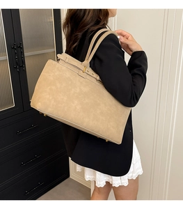 Detail of beige suede tote bag with gold metal buckle shown on shoulder of a model