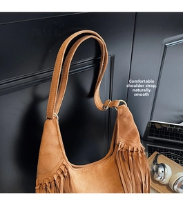 Détail d'un sac demi-lune en daim marron avec des franges denses et des bandoulières
