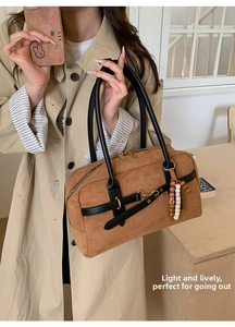 Close-up of brown suede Boston bag featuring ethnic beads and black leather straps