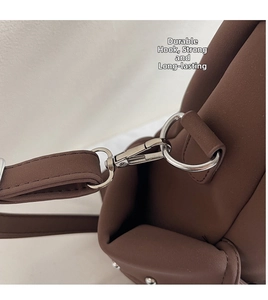 Détail du crochet en métal argenté et de la bandoulière de sac en similicuir marron mat
