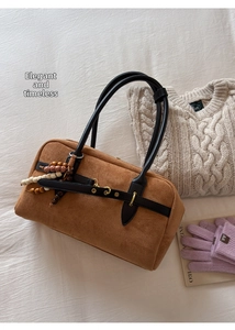 Close-up of brown suede handbag with black leather straps and colorful wooden beads