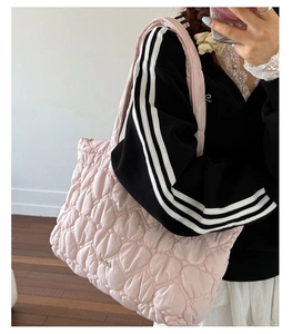Detail of pink quilted tote bag showing soft bubble texture and metallic heart logo