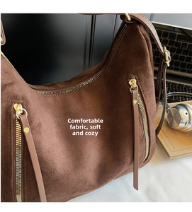 Close-up of brown suede shoulder bag featuring a premium gold zipper and leather puller