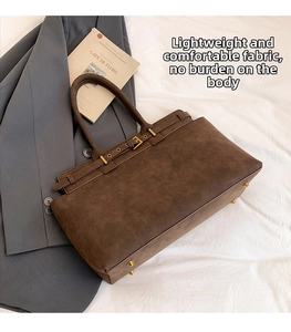 Detailed close-up of dark brown matte tote bag with gold buckle and metal feet hardware