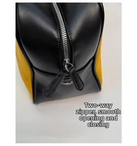 Detail of dual silver metal zippers on black leather and yellow canvas bag texture