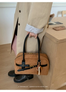 Close-up of brown suede Boston bag featuring black leather handles and vintage bead charm