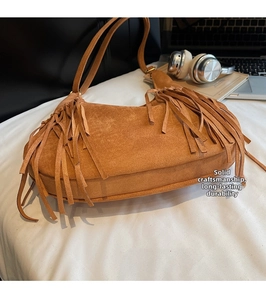 Vue détaillée du sac hobo en daim marron avec de longues franges bohèmes et texture vintage