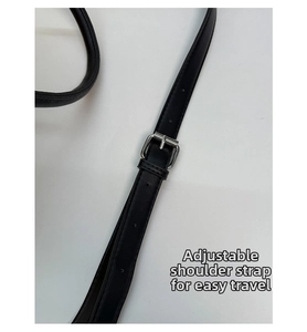 Close-up of black faux leather adjustable shoulder strap with silver metal buckle