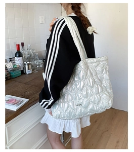 Detail of white quilted tote bag featuring heart patterns and pearlescent finish