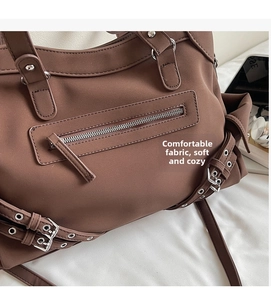 Détail du sac cabas marron foncé style biker avec œillets métalliques et fermetures