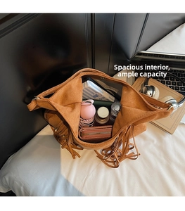 Intérieur spacieux du sac en daim marron à pompons avec accessoires du quotidien