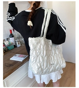 Detailed view of cream heart-quilted puffer tote bag showing texture and size on model