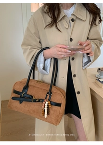 Detail of brown suede Boston bag with leather straps and wooden bead tassel decor
