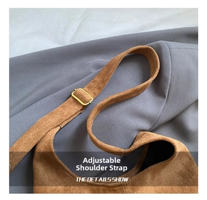 Détail de la bandoulière réglable et boucle dorée sur sac en daim marron