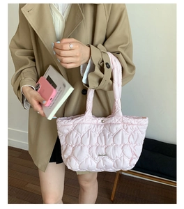 Close-up of pink heart quilted tote bag with metallic logo and secure top snap closure