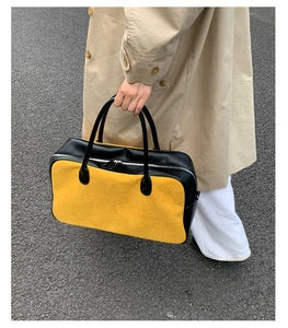 Detail of high-capacity canvas bag with yellow suede contrast and black leather handles