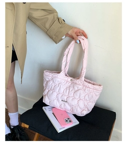 Pink quilted tote bag with heart stitch texture held by a model for size and style