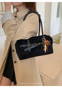 Detail of black retro suede shoulder bag with unique wooden bead tassel decoration