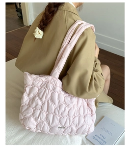 Detailed view of pink heart-quilted tote bag featuring a metallic logo and nylon texture