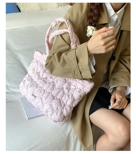Detailed view of pink quilted heart texture and metal logo on fashion tote bag