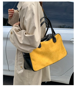 Outdoor street shot of a large yellow suede tote bag with black contrast trim on a model