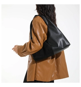 Macro shot of large black glossy leather tote bag showing material texture and capacity