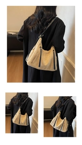 Detail of beige hobo tote bag featuring a long decorative zipper and black shoulder strap